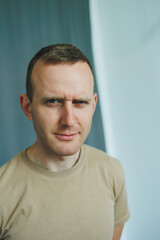 Fototapeta premium A confident young man in casual wear stands against a minimalist backdrop, showing his charming smile and relaxed pose. The image reflects creativity, modern masculinity, and youthful individuality