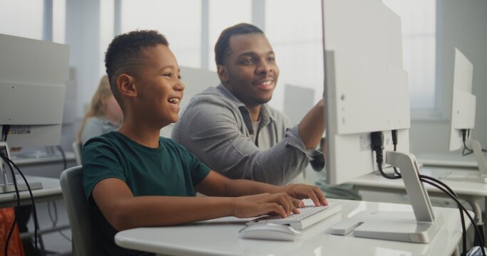 African American Smart Boy Using Computer, Doing Creative 3D Design Project. Teacher Helping Young Elementary School Student in Learning Coding During Digital Programming Lesson. Modern STEM Education