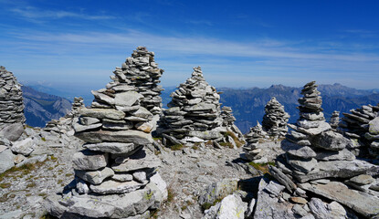 Stone cairns stacked on rocky mountain terrain under a clear blue sky, showcasing natural formations and the beauty of outdoor landscapes in a serene environment
