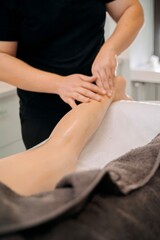 Professional massage therapist performing leg massage in spa