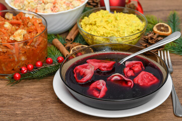 A rich Christmas Eve table in Poland, with salads, fish and red borscht with dumplings