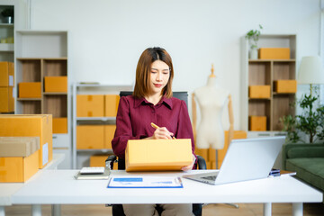 Asian SME entrepreneur prepares parcel for shipping in home office. ecommerce, delivery, packaging,...