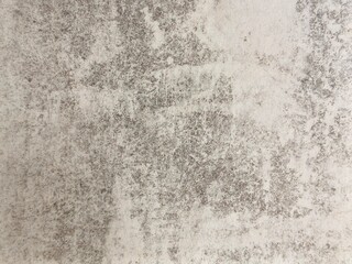 A close-up of a concrete wall reveals a mottled texture with shades of gray and white, giving it an aged and weathered appearance.