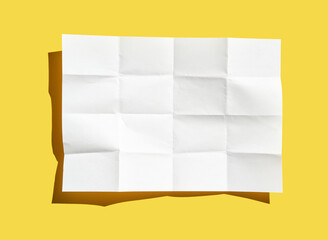 Crumpled white paper sheet on bright yellow surface with shadows.