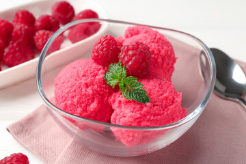 Delicious raspberry sorbet with mint in bowl, napkin and fresh berries on white table, closeup