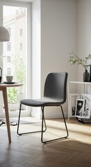 Fototapeta premium A contemporary gray velvet dining chair with black metal legs sits in a bright, minimalist dining area.
