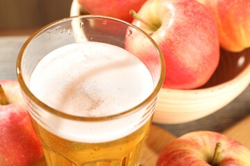 Delicious cider in glass and apples on table, closeup