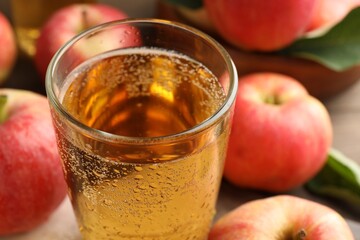 Delicious cider in glass and apples on table, closeup