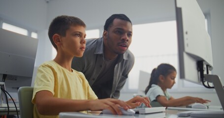 Smart Young Boy Using Computer, Doing Creative 3D Design Project. African American Teacher Helping Elementary School Student in Learning Coding During Digital Programming Lesson. Modern STEM Education