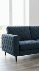 A contemporary, deep teal sectional sofa with a diamond quilted pattern rests elegantly on light hardwood floors, bathed in natural light.