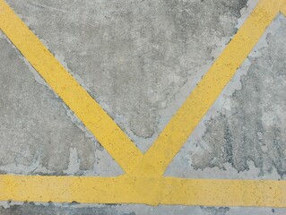 Yellow painted lines intersecting on concrete surface urban environment abstract image close-up perspective