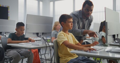 Primary School Students Working on Computers. African American Teacher Guiding Young Boy in Practicing Digital Skills and Studying Programming in Computer Science Classroom. Interactive STEM Learning.