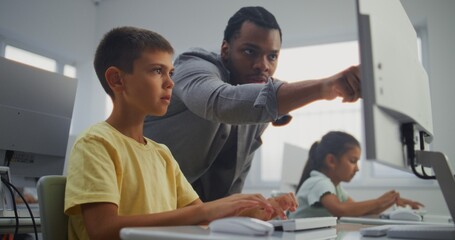 Smart Young Boy Using Computer, Doing Creative 3D Design Project. African American Teacher Helping Elementary School Student in Learning Coding During Digital Programming Lesson. Modern STEM Education