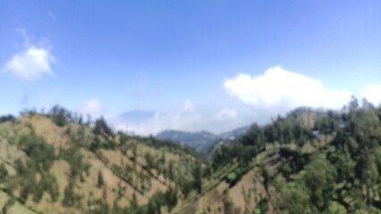 Obraz premium Beautiful mountain landscape with blue sky and clouds, showing natural hills and green trees. Perfect for travel blogs, tourism promotion, nature backgrounds, wallpapers, and educational materials.
