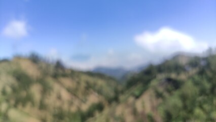 Blurred: A beautiful mountain landscape with blue skies and clouds, showcasing natural hills and green trees. Perfect for travel blogs, tourism promotions, nature backgrounds, wallpapers, and educatio
