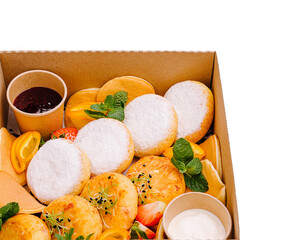 Delicious assortment of cottage cheese pancakes and savory snacks displayed in a takeout box