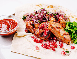 Delicious grilled meat served with pomegranate and fresh herbs on flatbread