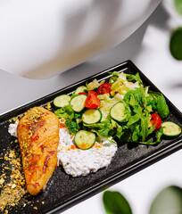 Grilled salmon with fresh salad and creamy dip served on black plate