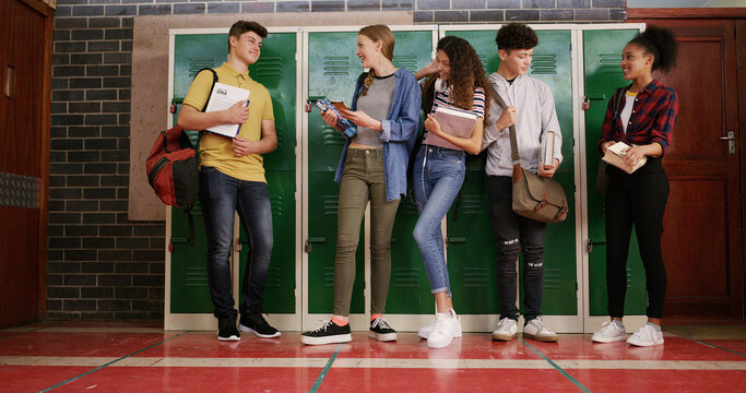 Students, teenagers and friends at high school for story, gossip or learning at recess. Education, happy people or group in conversation on break by lockers for study tips, chat or class at campus