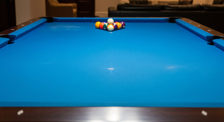 A perfectly set up blue billiard table with a vibrant rack of colorful pool balls, awaiting the start of an engaging game in a cozy recreational room, ready for leisure or competitive play