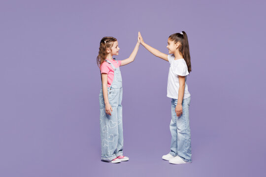 Full body little two friends kids children girls 9-10 years old wear casual clothes meet together greeting give high five clapping hands folded isolated on plain purple background. Lifestyle concept.