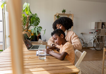 Young woman with son writing on note pad at home