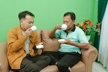 Two men are enjoying a warm and friendly moment together over a cup of tea in a cozy atmosphere