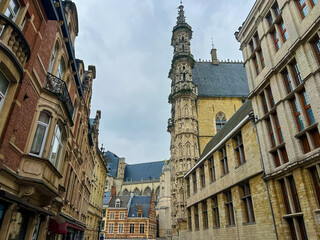 Obraz premium Charming old street view of Leuven town hall with ornate buildings and church tower