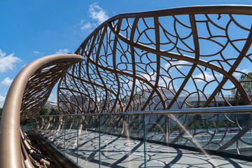 Metal installation features flowing, organic patterns that create dome  under clear blue sky. Close...