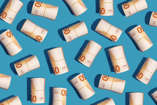 Rolls of fifty euro notes arranged on blue background in studio