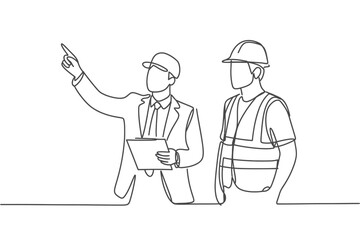 Two construction workers in hard hats discussing plans on a site