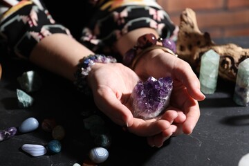 Woman with healing stones at black table, closeup