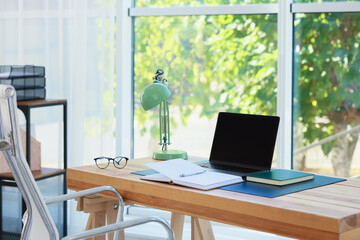 Home workplace. Laptop and stationery on wooden table