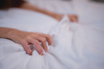 Woman lying in bed, clutching soft white sheets, experiencing intense pleasure and orgasm, embodying the essence of female sexuality and intimate self-exploration