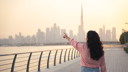 young woman enjoying the view of birds in Dubai with Dubai skyline background at sunset, waterfront location stock photo
