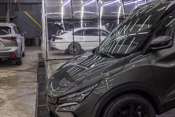Dark gray SUV parked in indoor car wash detailing studio during daytime