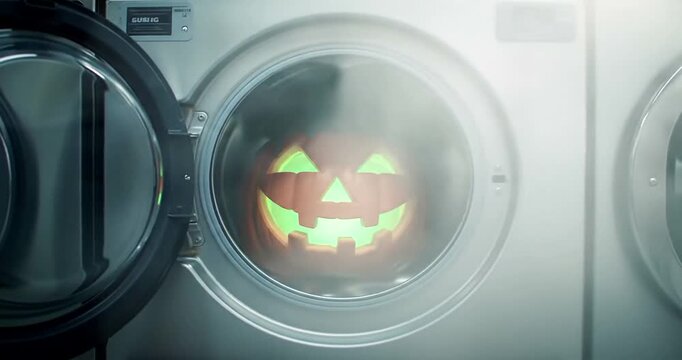 Scary Halloween pumpkin glowing inside a washing machine.