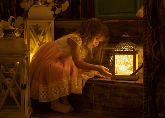 Girls look at lantern with golden light in cozy room decorated for Christmas.
