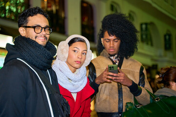 Friends using smartphone and walking in city center during winter