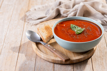 Homemade Tomato Soup in bowl with Basil on wooden table. Copy space
