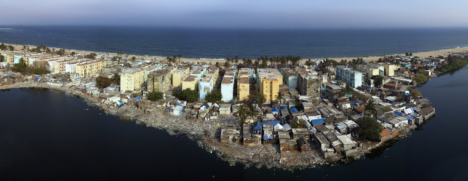 Aerial view of buildings stand in contrast to the sprawling coastline and dark water, while the city reveals a tapestry of urban life, Chennai, Tamil Nadu, India.