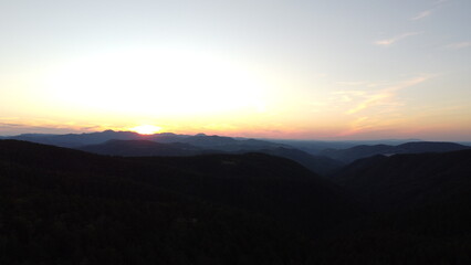 Fototapeta premium Sunset Over Mountain Range and Forest – Aerial View Landscape 