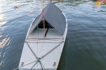 Small boat docked at pier with canopy and ropes in calm marina setting. Dockside marine lifestyle with small boat tied at pier under improvised tarp ideal for travel adventure craftsmanship.