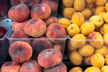 Fresh fruits including nectarines, peaches and apricots in market display. Colorful arrangement of ripe stone fruits in transparent containers showcasing seasonal produce in grocery market setting.