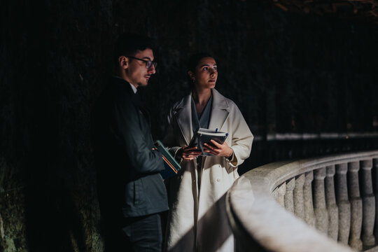 Two people stand near a museum railing in thoughtful contemplation, holding notebooks, with dim atmospheric lighting enhancing the scene's elegance and intellectual ambiance.