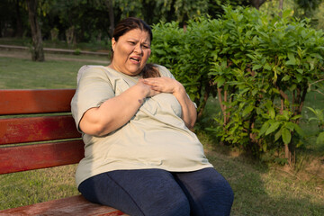Indian plus size woman suffering chest pain at park