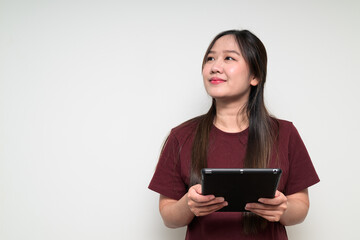 Fototapeta premium Studio portrait of young Asian woman using digital tablet computer while thinking and looking up