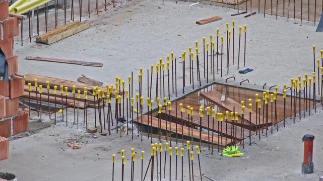 Construction Site with Metal Reinforcement Rebar Rods Secured with Yellow Safety Caps to Prevent Workplace Accident Injury