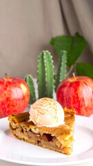 Slice of apple pie with ice cream, surrounded by apples and cacti