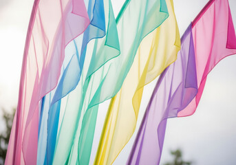 Rainbow flags waving in the wind against a bright sky.